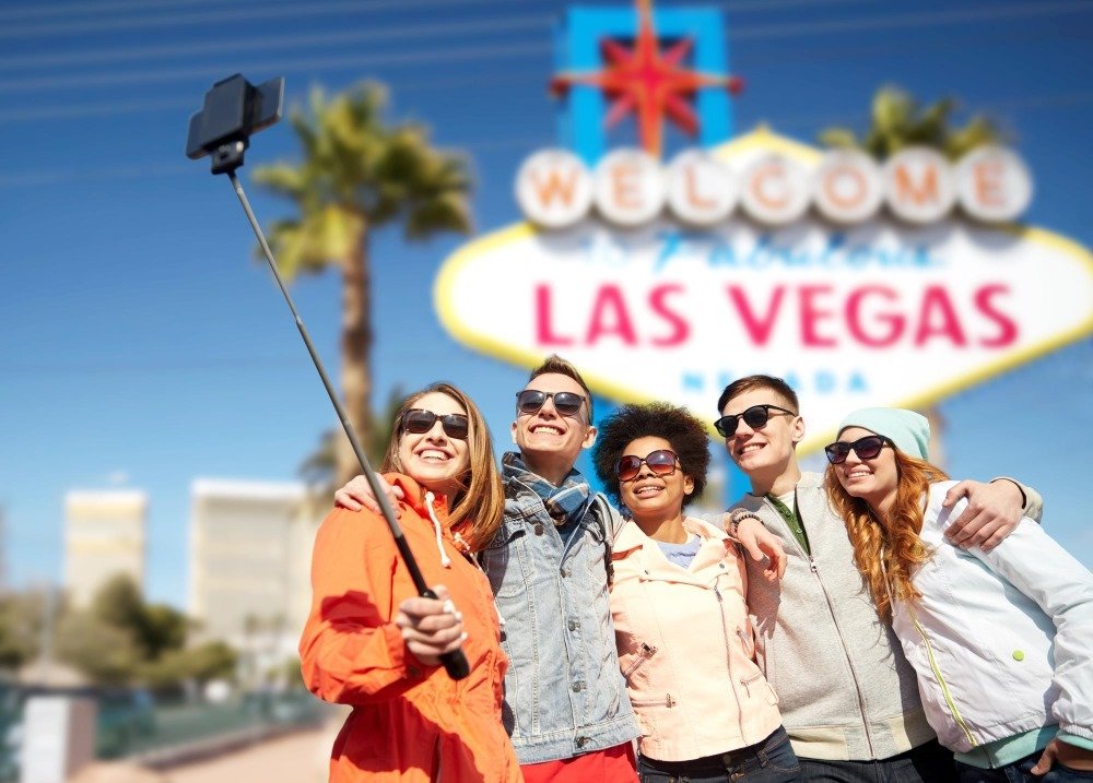 A group of happy tourists taking a selfie in front of the iconic "Welcome to Fabulous Las Vegas" sign during a Las Vegas Strip tour.