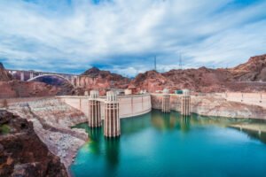 Panoramic view of Hoover Dam and Memorial Bridge surrounded by desert mountains, featured in our Hoover Dam tours from Las Vegas.