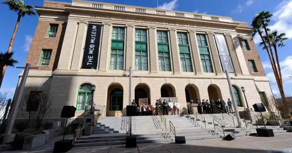 Entrance of The Mob Museum in Las Vegas, displaying its grand facade with large steps leading to the main doors under clear blue skies, surrounded by palm trees, highlighting its historical and educational significance.