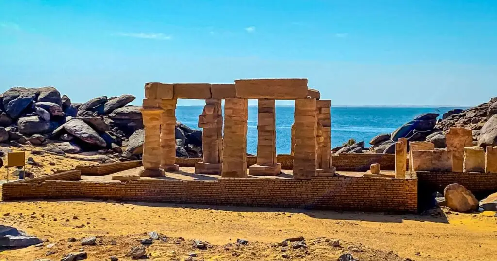 Ancient stone ruins by the sea with clear blue skies, resembling historical structures